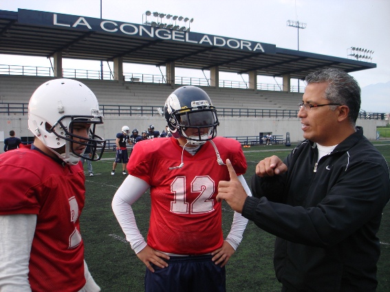 Coach Fay Suárez con sus quarterbacks